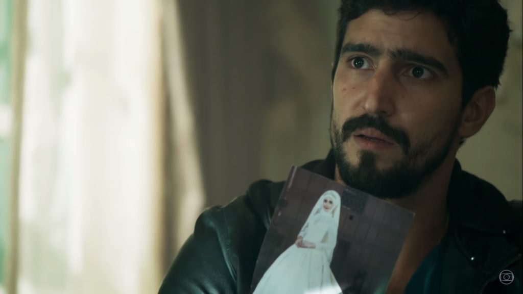 Aziz (Herson Capri) mostra foto de Laila (Julia Dalavia) para Jamil (Renato Góes) em Órfãos da Terra