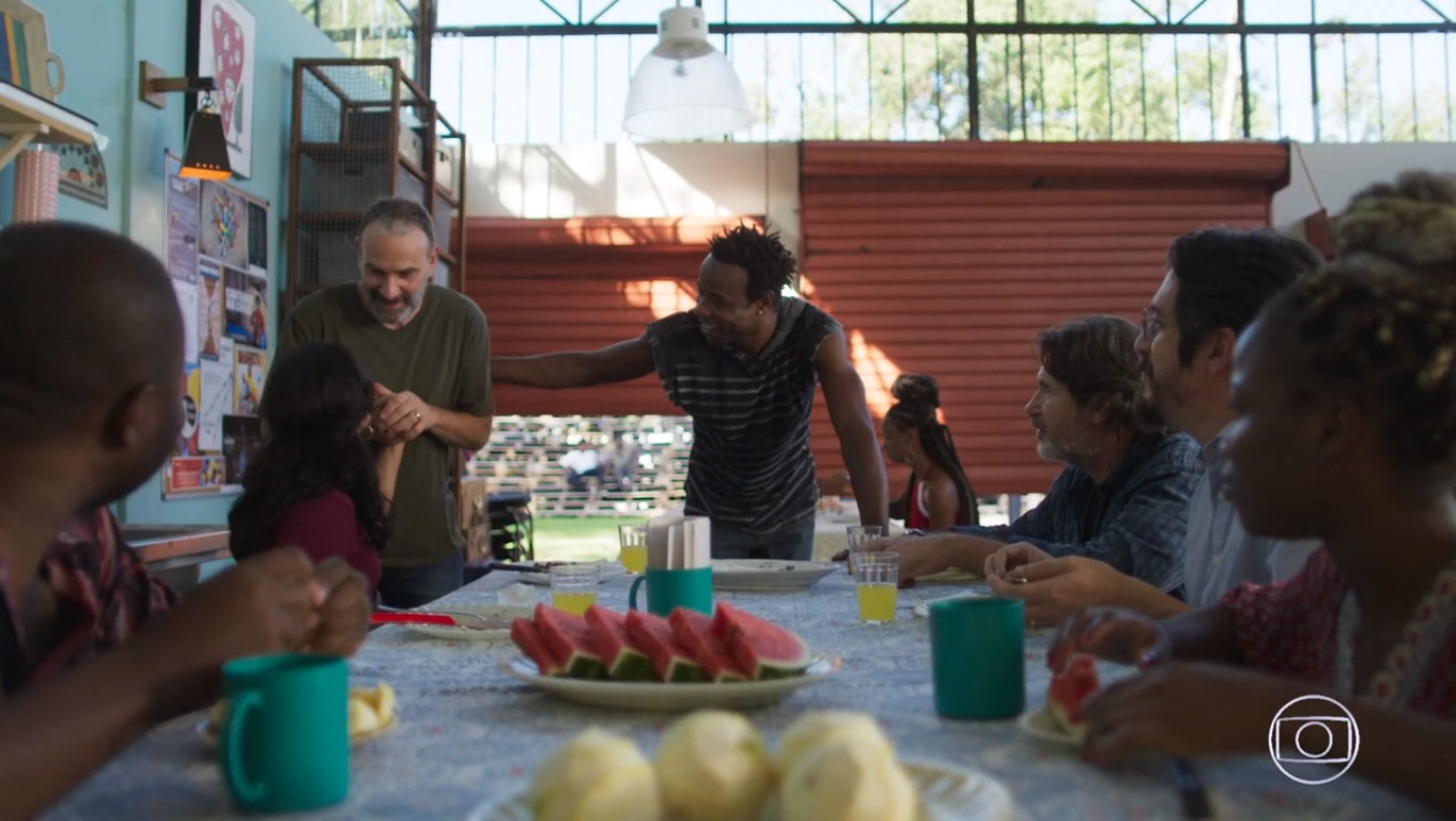 Elias (Marco Ricca) e Missade (Ana Cecília Costa) são recebidos no campo de refugiados no Brasil em Órfãos da Terra