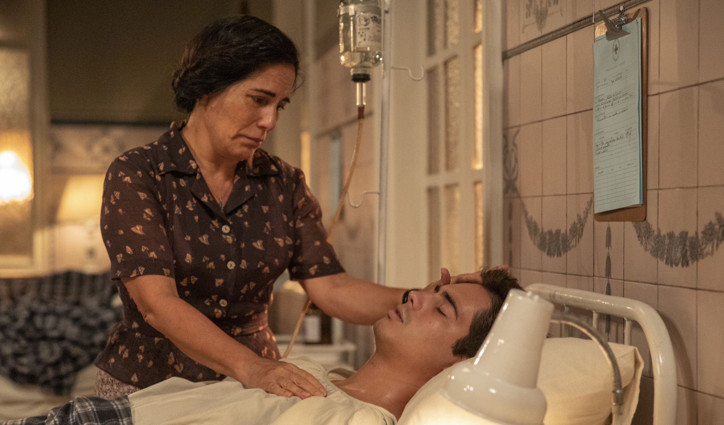 Alfredo (Nicolas Prattes) entra no quarto, onde estão Lola (Gloria Pires), Clotilde (Simone Spoladore) e Isabel (Giullia Buscacio), ao lado de Carlos,em seus últimos momentos. *** Local Caption *** Capítulo 111 – Cena 18 – Alfredo (Nicolas Prattes) entra no quarto, onde estão Lola (Gloria Pires), Clotilde (Simone Spoladore) e Isabel (Giullia Buscacio) ao lado de Carlos, que ainda dorme no leito.