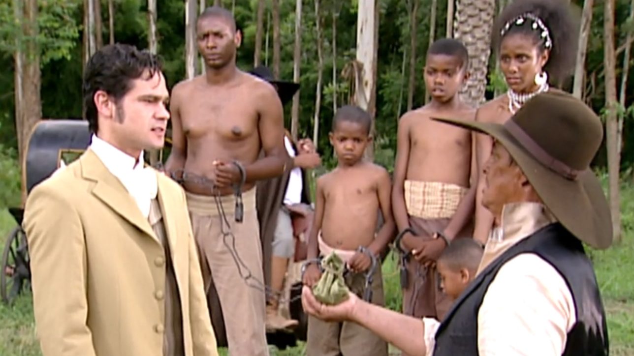 Henrique (Gabriel Gracindo) compra Moleca (Bárbara Garcia) e as crianças com dinheiro falso em A Escrava Isaura