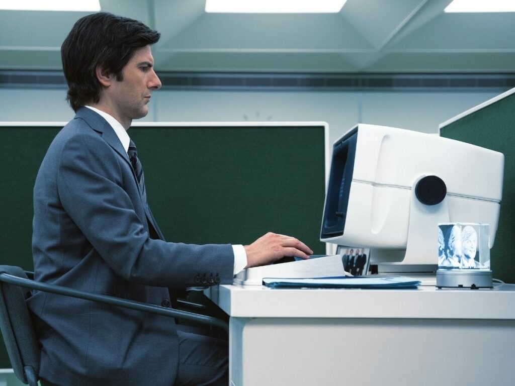 Adam Scott mexe em computador arcaico na série Ruptura